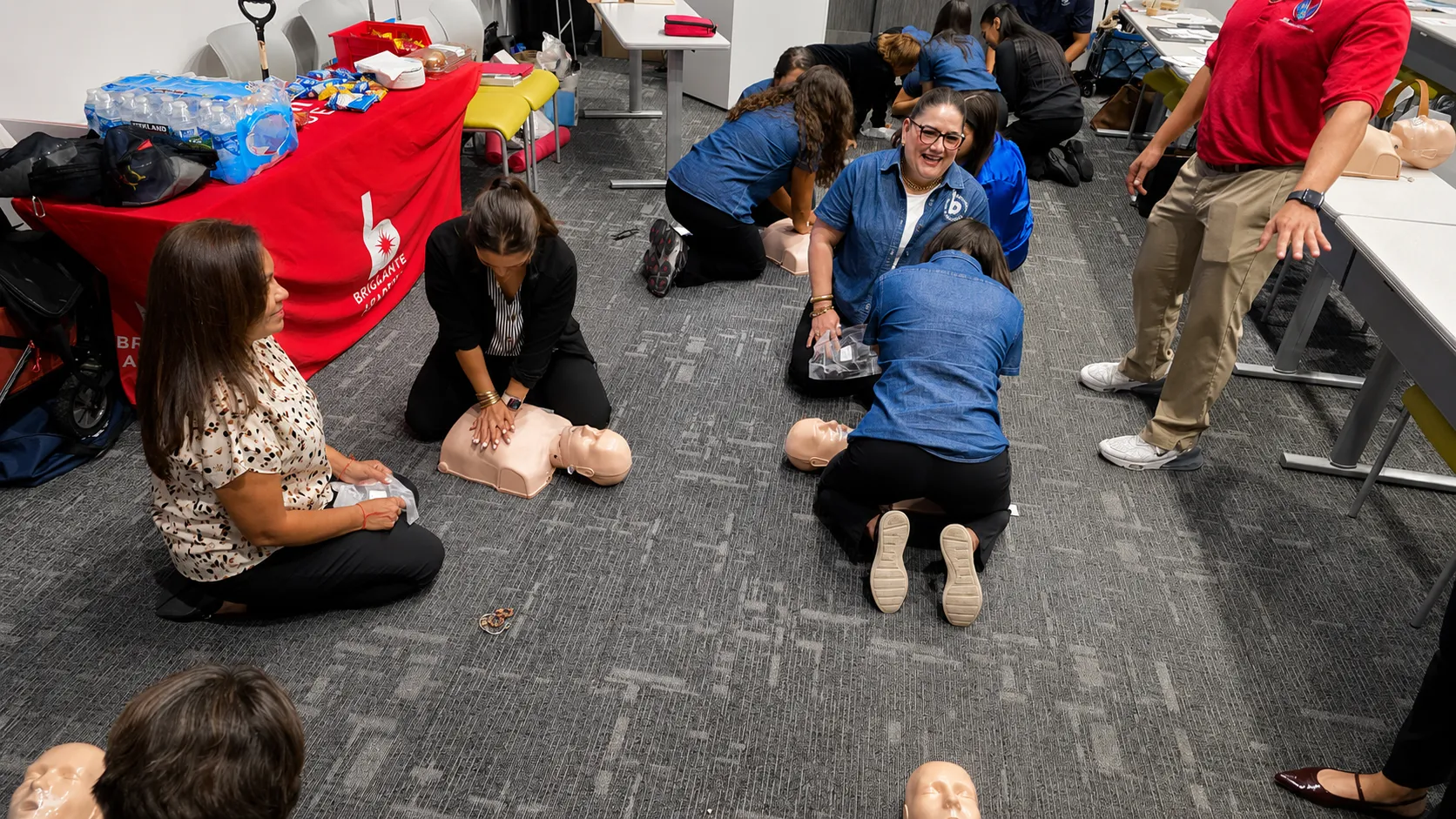 Participants practicing chest compressions on manikins while a CPR Masters RGV instructor supervises during a group class.